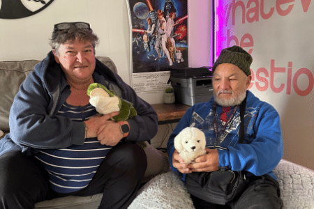 Two NDIS participants sitting in lounge room holding a toy animal each