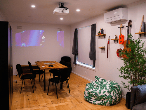 Living and dining area with table and chairs, beanbag and projector on wall