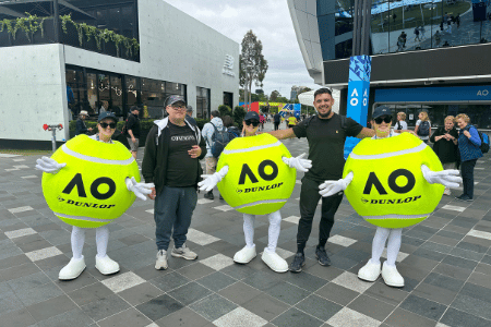 NDIS participant and support worker at the Australian Open standing next to three people dressed up as tennis balls