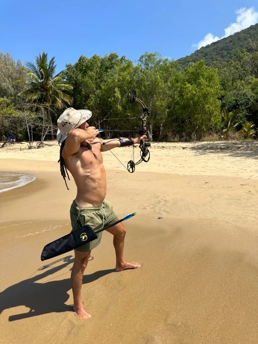 A man doing archery on the beach