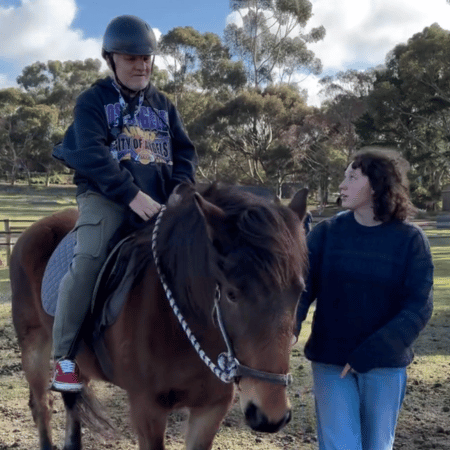 An disabled man riding a horse and his support worker